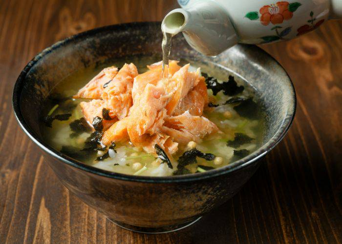 Salmon ochazuke: tea is being poured over a prepared bowl of flaky salmon and cooked rice.