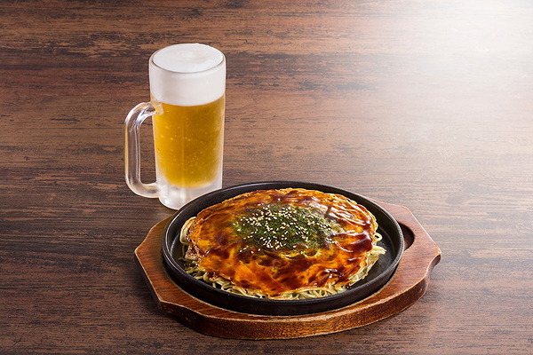 Savory Japanese okonomiyaki with frosty beer on wooden table