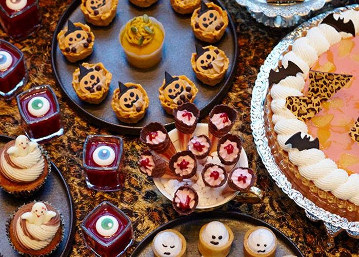 A sweets buffet with ghost meringues, tarts, cupcakes, and Halloween-themed desserts
