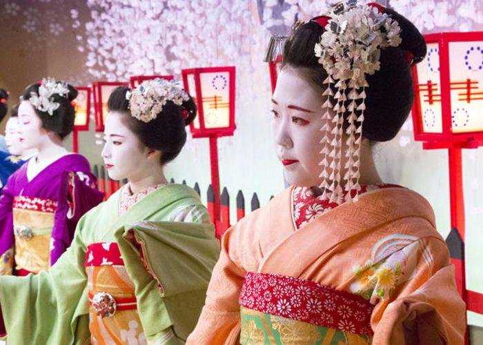 Maiko and geiko drssed in colorful Japanese kimono, with their faces painted white and lips red
