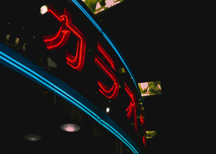 A neon sign of the front of a karaoke bar. It says karaoke in katakana.