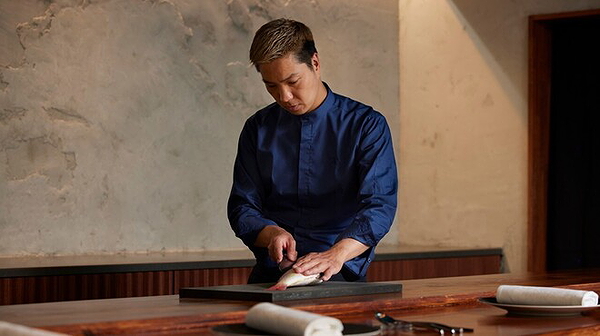Chef preparing dish at a rustic restaurant countertop.