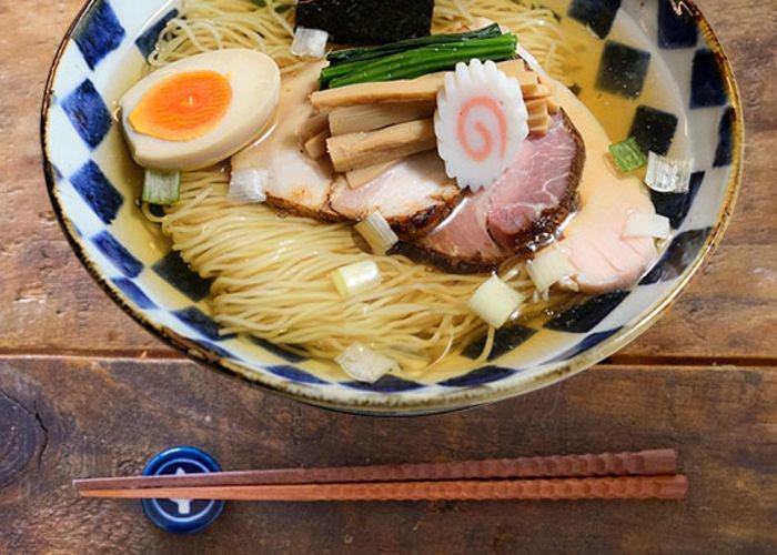 Bowl of ramen, with thin straight noodles topped by egg, naruto, chashu pork, menma