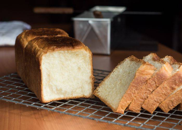 Four slices cut off a fresh loaf of Japanese milk bread and leaning diagonally.