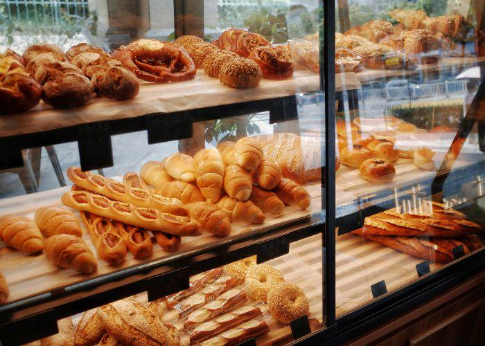 The shelves of a bakery, filled with freshly baked rolls, baguettes, croissants and more.