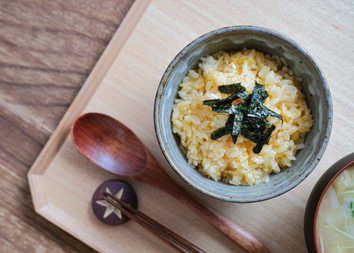 A classic Japanese breakfast: Tamago kake gohan, featuring steamed rice with raw egg stirred in and seaweed on top.