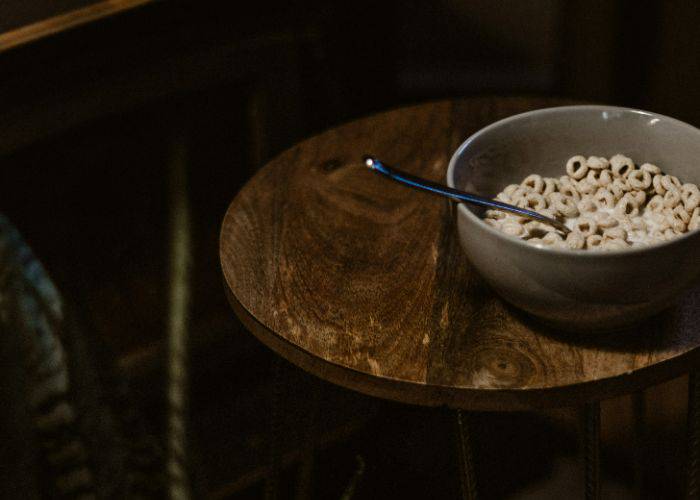 A bowl of cereal on a dark, wooden stool.