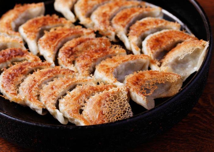 Pan-fried gyoza dumplings nestled in a dark iron skillet, with crispy brown bits facing upwards