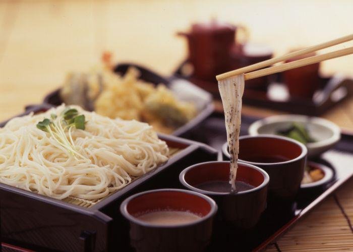 Chopsticks holding Shiroishi umen dipped in sauce