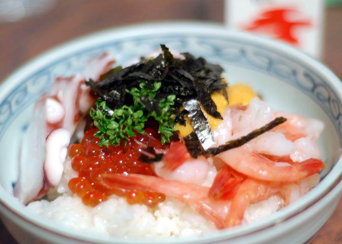 A rice bowl covered with fresh raw seafood