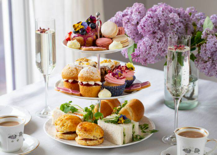 The elegant afternoon tea of Moska by Ginger Garden, featuring tea, cakes, finger sandwiches and blooming flowers.