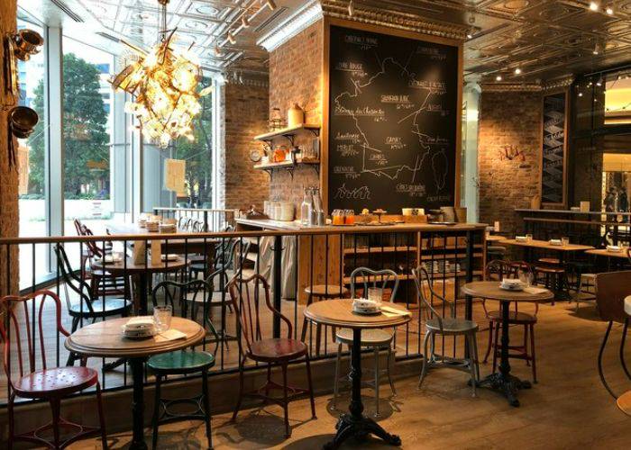 The industrial interiors of Buvette, featuring exposed brick, metal chandeliers and a mix of iron and warm woods.