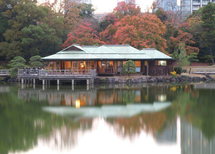 The serene scenes of Hamarikyu Gardens with a backdrop of reds and oranges.