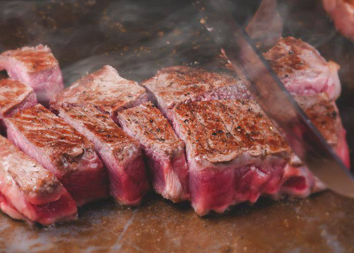 Premium Kobe beef being grilled while being sliced through.