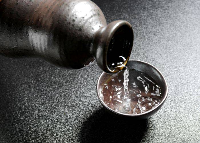 A bottle of sake being poured into a sake cup.