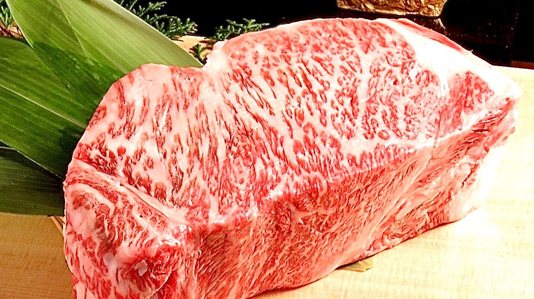 A large slab of marbled Kobe beef sitting on a table at Kobe Steak and Cafe Noble Urus Sannomiya