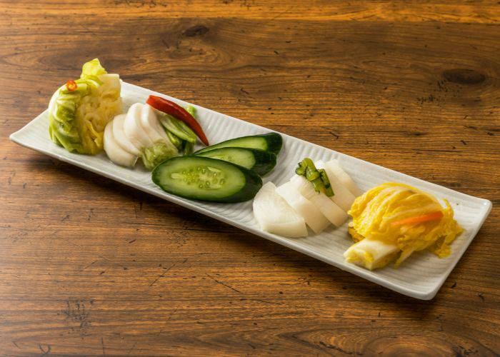 A tray with a selection of pickled vegetables, including cucumber and radish.