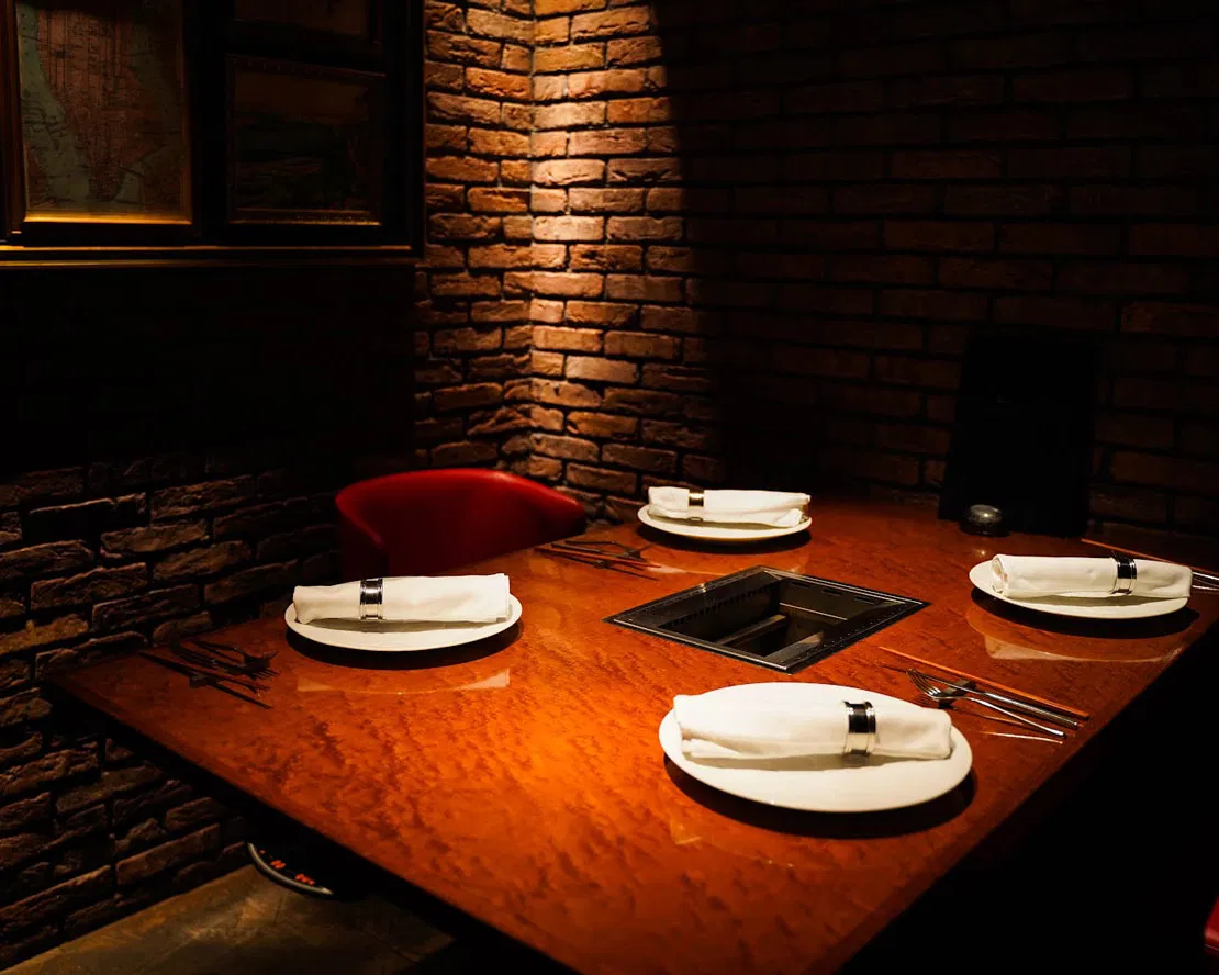 The exposed brick wall and chic dining space of YAKINIKU 37west NY.