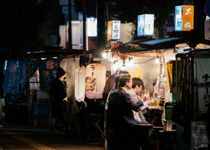 A salaryman drinking beer at a food stall in Japan.