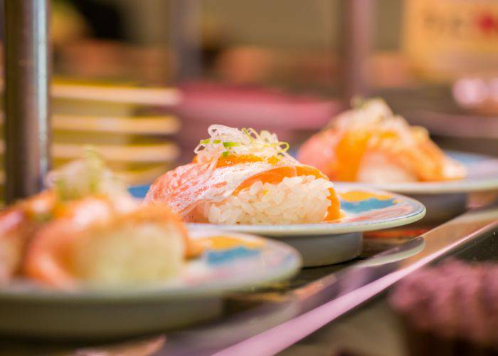 Three plates of sushi zooming past at a conveyor belt sushi restaurant.