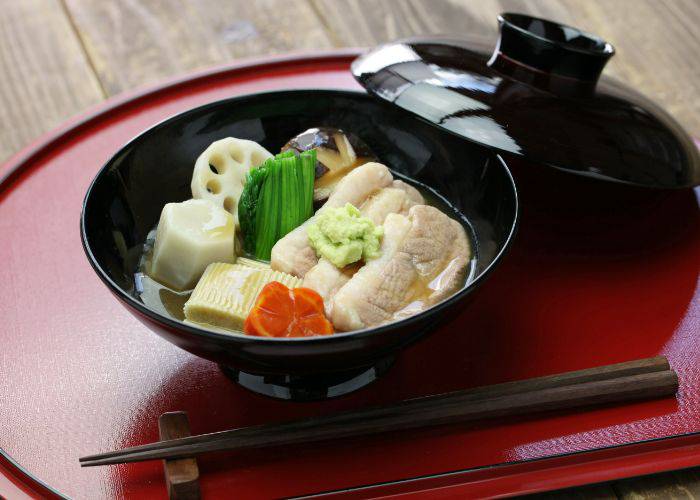 A bowl of jibuni, featuring duck, veggies and wasabi soaking in broth.