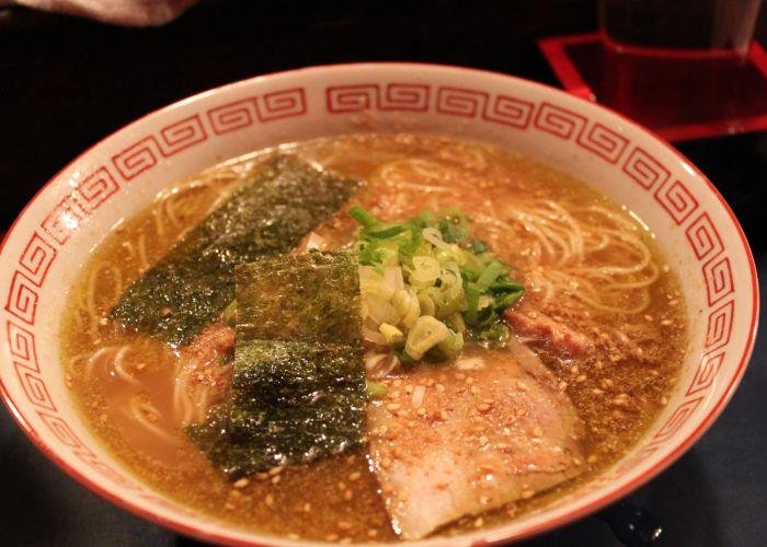 A bowl of Hakata ramen with seaweed, sesame, noodles and pork