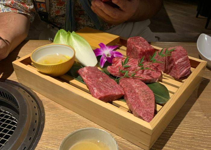 Thick, marbled cuts of premium wagyu beef, served alongside lettuce, sake and flowers.