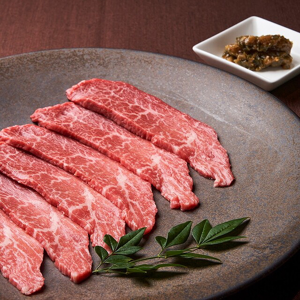 Fresh Wagyu beef slices on a stone plate with herb garnish