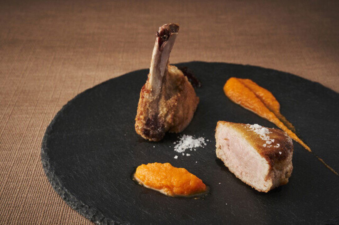 Gourmet lamb rack with purée on a dark plate