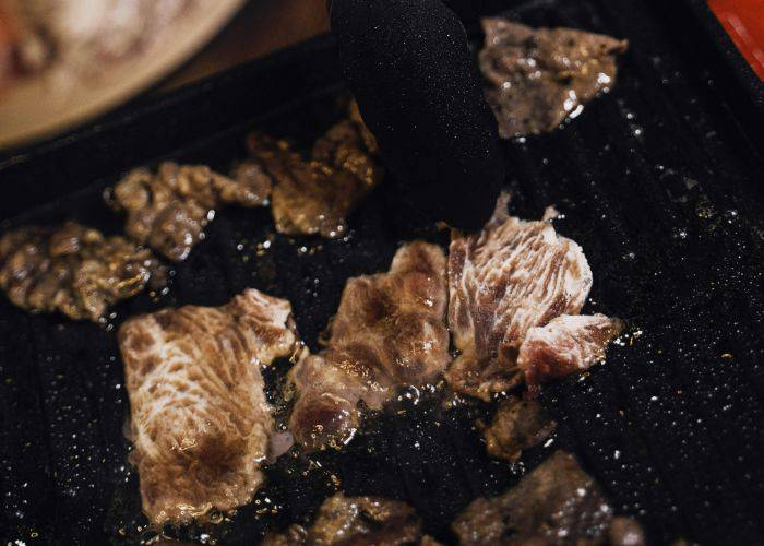 Small cuts of wagyu beef being grilled.