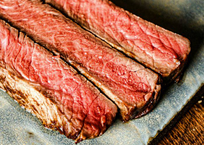 Three cuts of grilled wagyu beef, crispy and brown around the edges while still pink in the center.