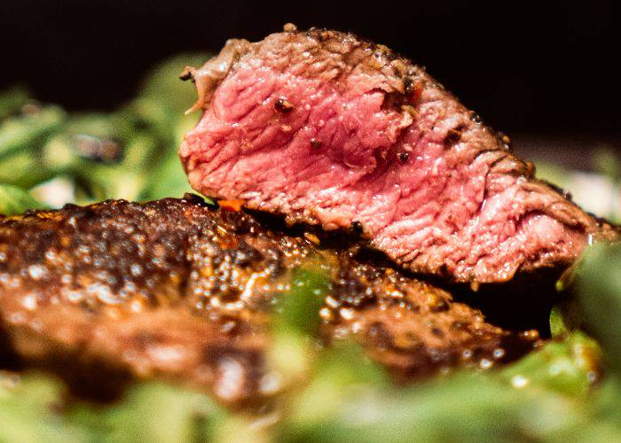 Chunky, medium-rare cuts of wagyu beef, surrounded by greens.