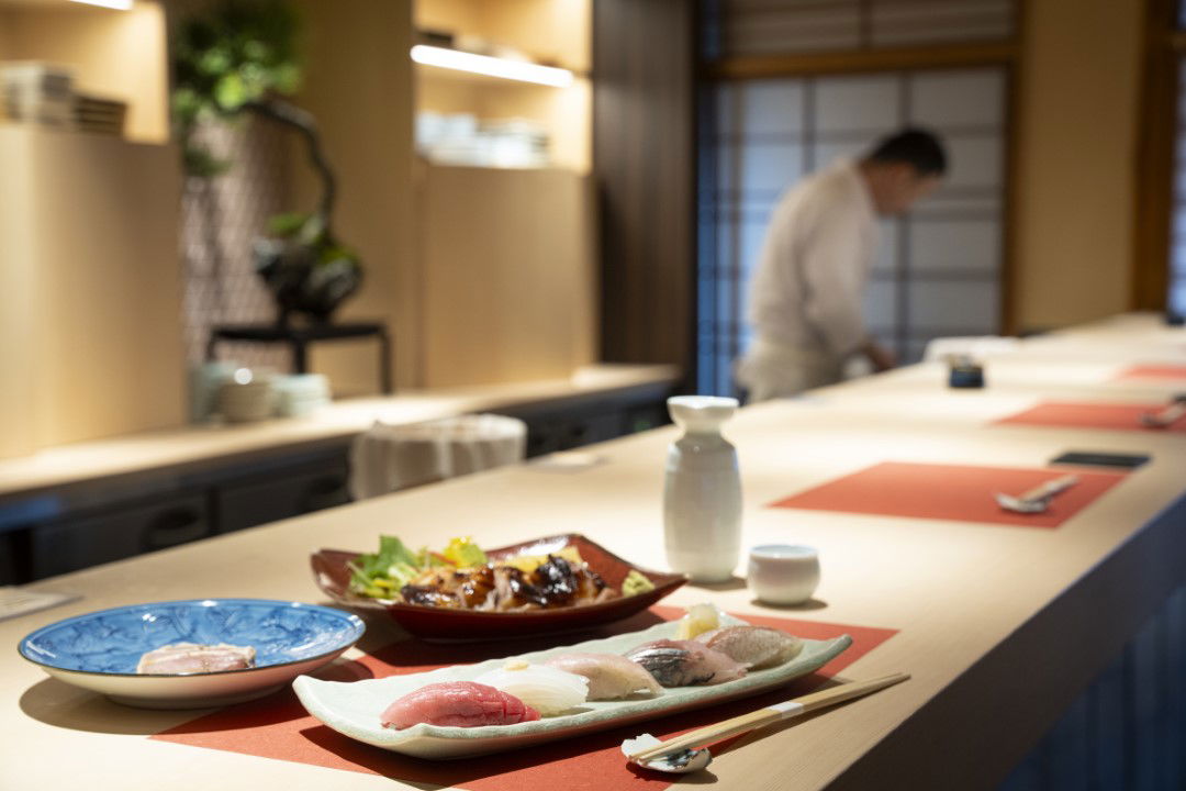 A selection of sushi and side dishes on the sleek counter of OBENKEI Kyoto Gion.