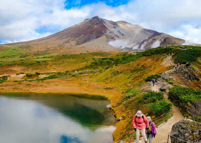 Two hikers walking the trail of Asahidake (Hokkaido) as the scenes begin to turn orange.