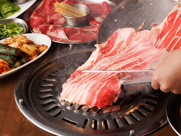 Korean BBQ grilling fresh meat with side dishes