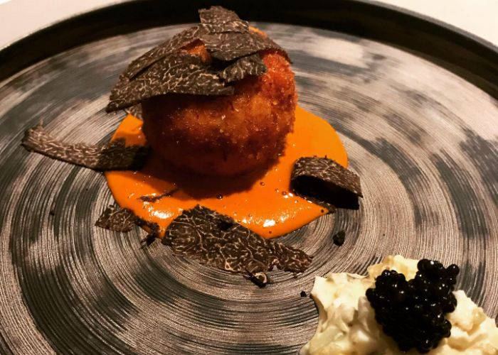 A delicate plating of crab croquette at NISHIAZABU K+, resting on a circle of sauce and topped with seaweed.