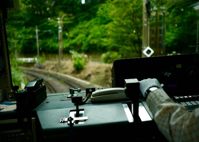 A train conductor in Japan, wearing gloves and controlling the train.