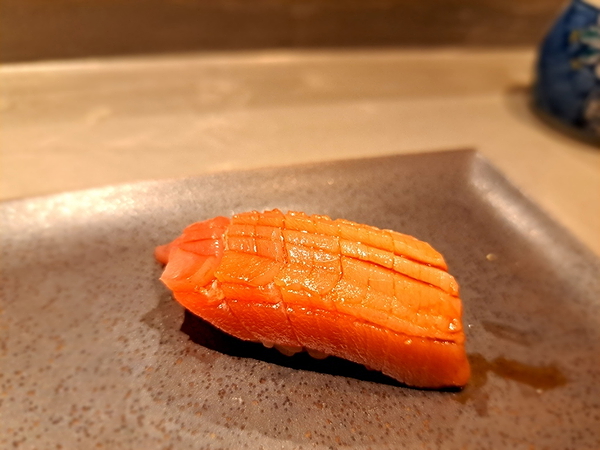 Gourmet salmon nigiri on ceramic plate in upscale restaurant