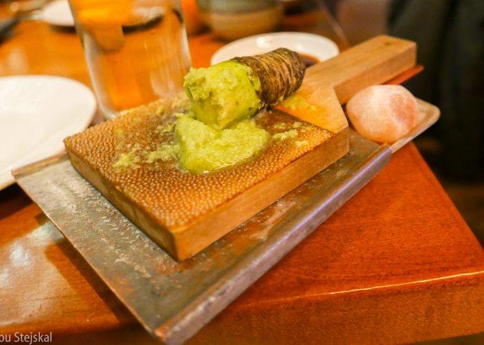 Wasabi root freshly ground by a grater on a table