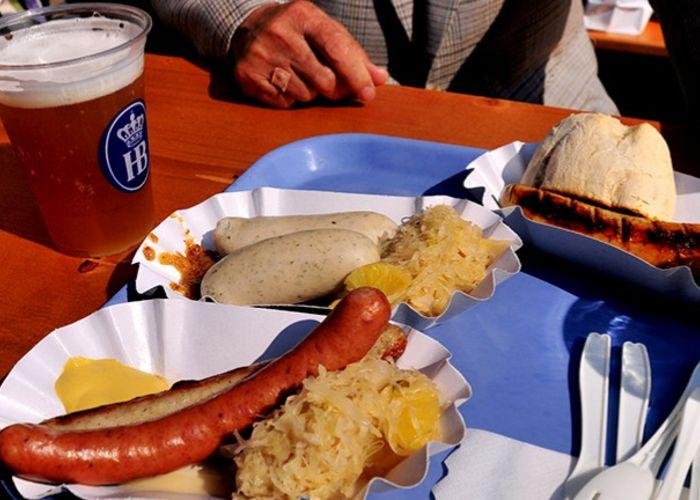 A table with a pint of beer and two buns with German sausages in and sauerkraut