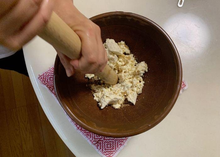 The Japanese mortar and pestle (suribachi and surikogi) are being used to mash a mix of tofu and sesame seeds