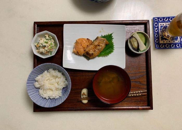 An image of "Ichijiu Sansai," the traditional Japanese meal layout with one soup and three dishes. There is a bowl of white rice, miso soup, shiroae, Japanese pickles, and grilled salmon