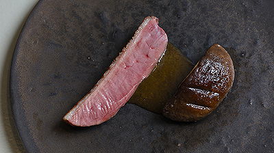 Gourmet steak dish served with rich sauce on a dark ceramic plate