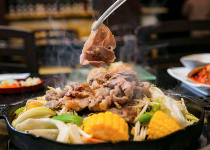 A cooked cut of meat being lifted from the unique jingisukan Hokkaido yakiniku grill.