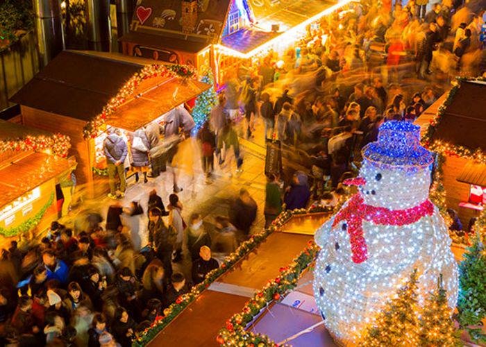 An aerial shot of the German Christmas Market in Osaka, with a large sparkling Christmas tree and crowds rushing below