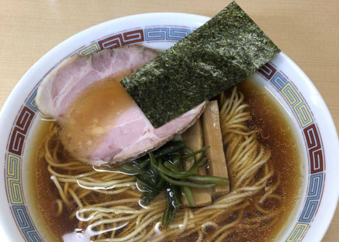 A broth-filled bowl of ramen, with noodles, pork and seaweed soaking in the flavors.