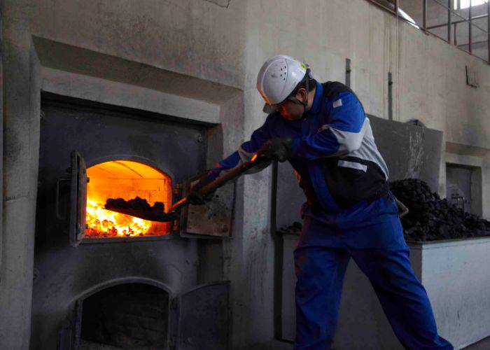 A worker at a NIKKA WHISKY distillery, shoveling more coal into the furnace.