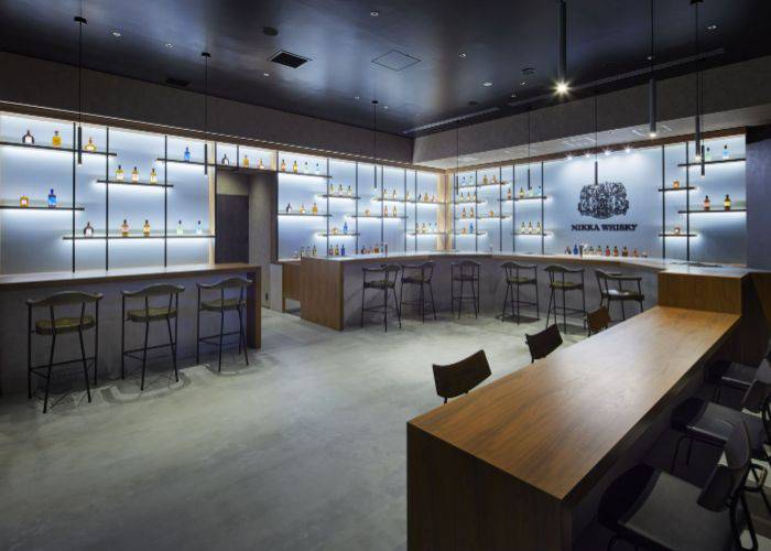 The Bar at THE NIKKA WHISKY TOKYO, featuring chic, backlit shelves filled with NIKKA WHISKY bottles.