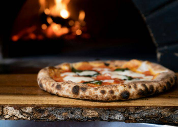 A fresh pizza that's been recently taken from the fiery pizza oven.