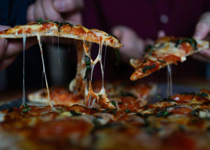 Stringy slices of margherita pizza being picked up.